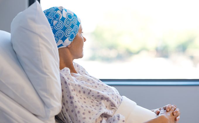 A woman in a hospital bed gazes out the window.