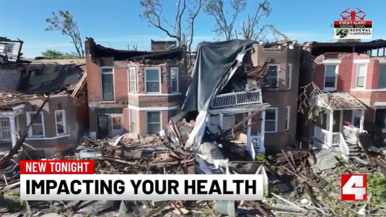 Ruined brick townhouses with collapsed roofs and rubble covering the street; bottom news banner reads 'NEW TONIGHT IMPACTING YOUR HEALTH'.
