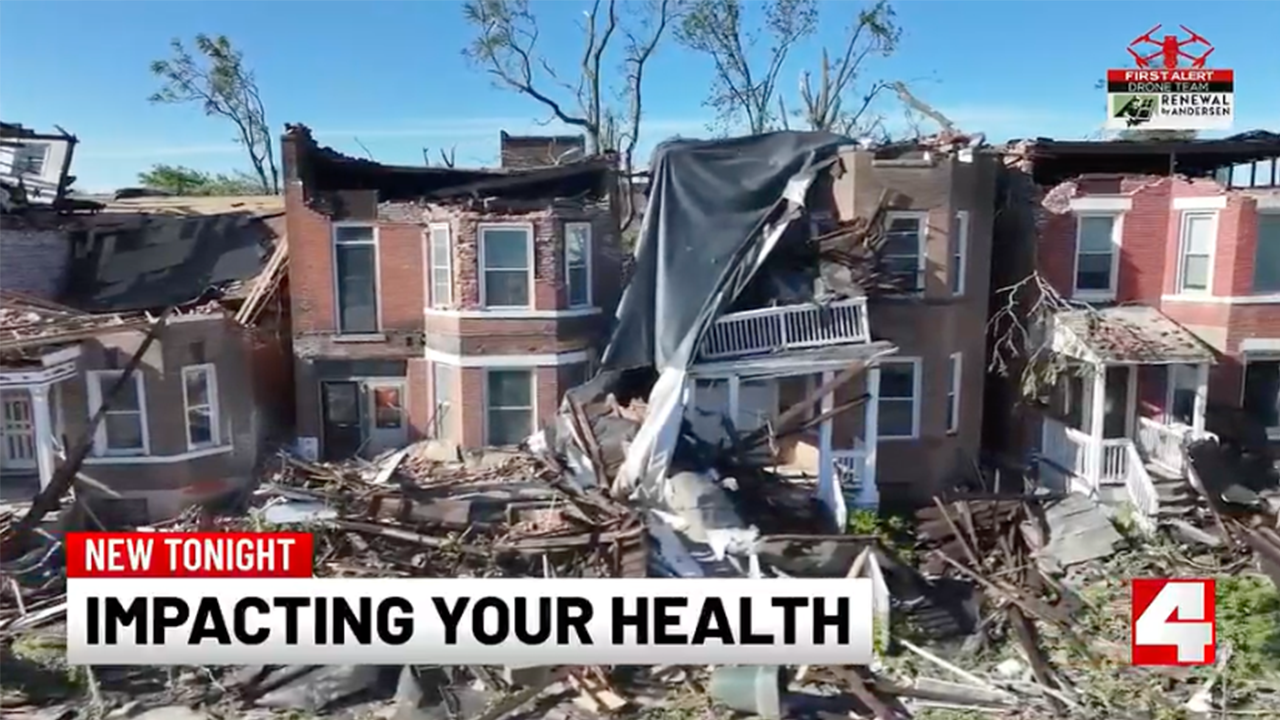 Ruined brick townhouses with collapsed roofs and rubble covering the street; bottom news banner reads 'NEW TONIGHT IMPACTING YOUR HEALTH'.