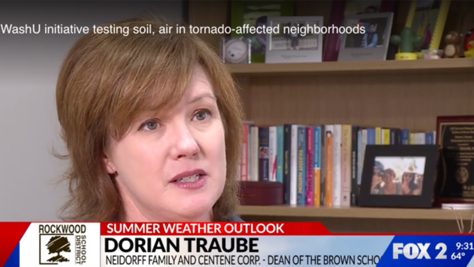 Woman being interviewed in a TV news segment about weather, with a bookshelf in the background.