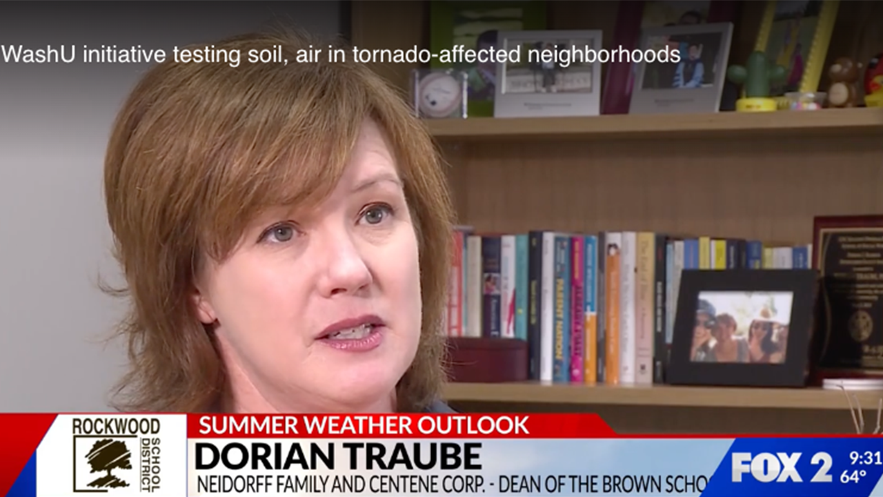 Woman being interviewed in a TV news segment about weather, with a bookshelf in the background.