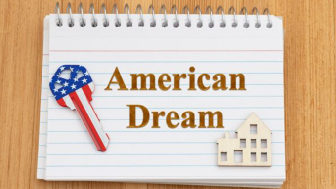 Notebook page with 'American Dream' text, a key decorated like the American flag, and a small house cutout on a wooden surface.