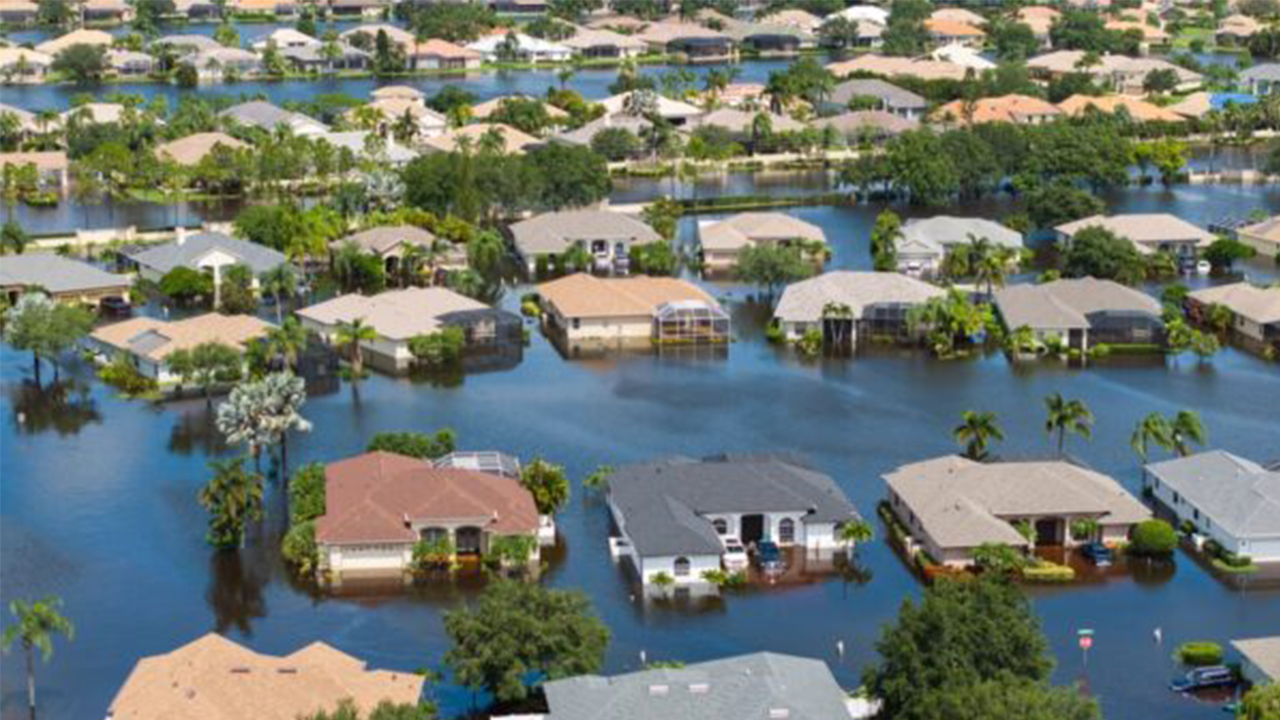 Submerged suburban neighborhood with floodwater surrounding yards and houses from an aerial view.