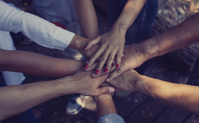 Group of people putting hands in the center of a circle.