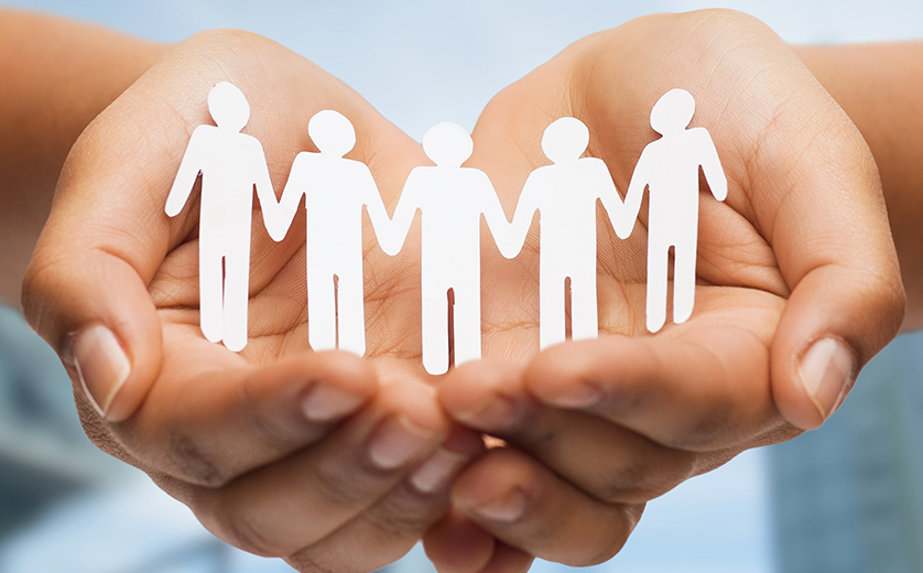 Photo of cupped hands holding row of paper cutout of people