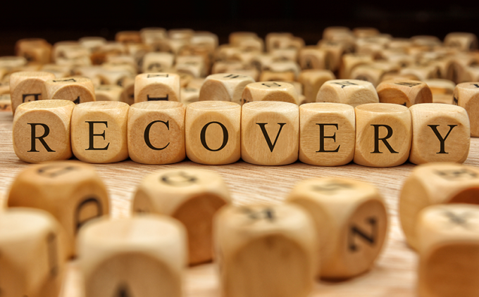 Letter tiles spell out recovery on a tabletop