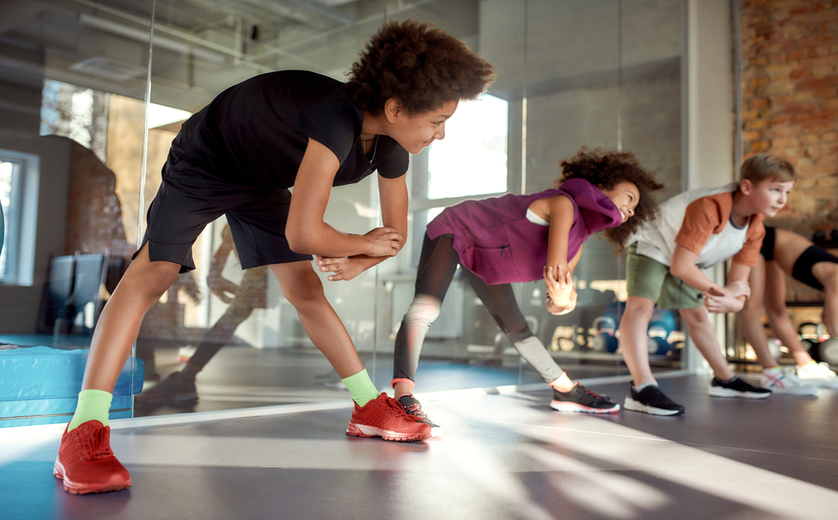 Kids in sundrenched gym doing calisthenics