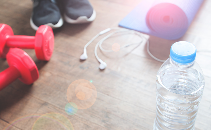 Ipods, workout gear on wood floor Person wearing sneakers stands nearby