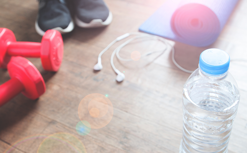 Ipods, workout gear on wood floor Person wearing sneakers stands nearby